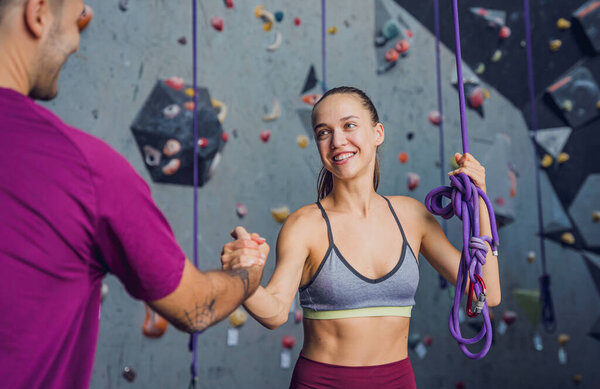 A strong couple of climbers against an artificial wall with colorful grips and ropes