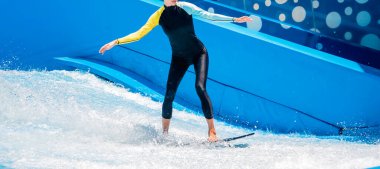 Su parkında dalga simülatöründe sörf yapan güzel bir genç kadın..