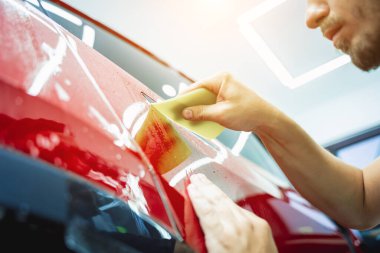 Yeni kırmızı arabaya koruyucu film yükleme işlemi