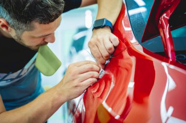 Yeni kırmızı arabaya koruyucu film yükleme işlemi