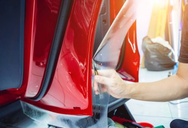 Yeni kırmızı arabaya koruyucu film yükleme işlemi