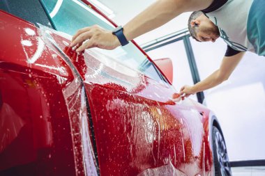 Yeni kırmızı arabaya koruyucu film yükleme işlemi