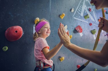 Yapay duvarda fotoğrafçıya poz veren güçlü bir bebek tırmanıcı.
