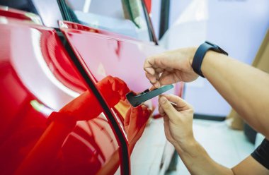 Yeni kırmızı arabaya koruyucu film yükleme işlemi