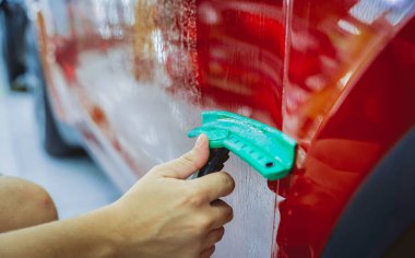 Yeni kırmızı arabaya koruyucu film yükleme işlemi