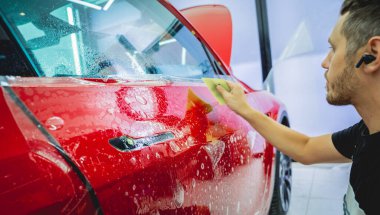 Yeni kırmızı arabaya koruyucu film yükleme işlemi