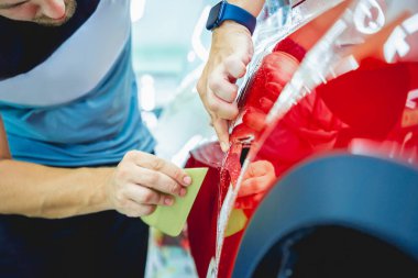 Yeni kırmızı arabaya koruyucu film yükleme işlemi