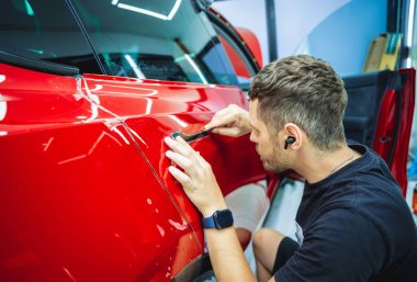 Yeni kırmızı arabaya koruyucu film yükleme işlemi