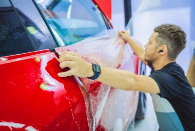 Yeni kırmızı arabaya koruyucu film yükleme işlemi