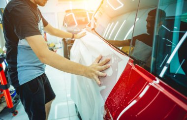 Yeni kırmızı arabaya koruyucu film yükleme işlemi