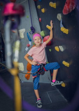 Yapay duvarda fotoğrafçıya poz veren güçlü bir bebek tırmanıcı.