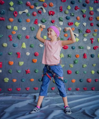 Yapay duvarda fotoğrafçıya poz veren güçlü bir bebek tırmanıcı.