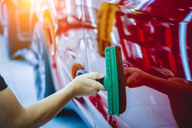 Yeni kırmızı arabaya koruyucu film yükleme işlemi