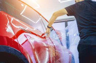 Yeni kırmızı arabaya koruyucu film yükleme işlemi