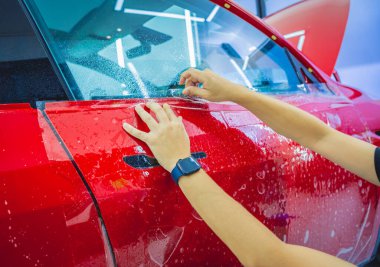 Yeni kırmızı arabaya koruyucu film yükleme işlemi