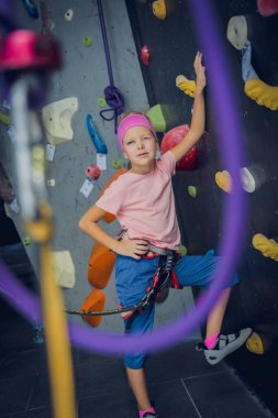 Yapay duvarda fotoğrafçıya poz veren güçlü bir bebek tırmanıcı.