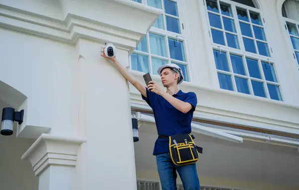 技術者が住宅ビルの正面にCctvカメラを設置する — ストック写真