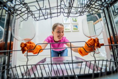 Genç kadın bulaşık makinesinden bulaşıkları çıkarıyor..