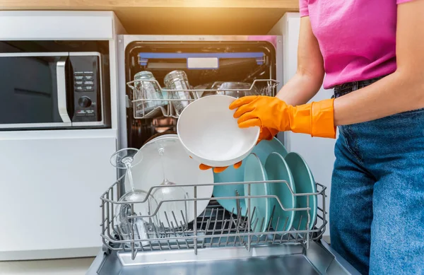 Genç kadın bulaşık makinesinden bulaşıkları çıkarıyor..