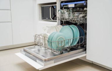 Genç kadın bulaşık makinesinden bulaşıkları çıkarıyor..