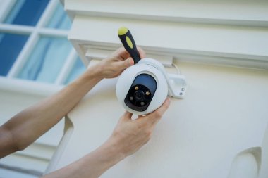 Bir teknisyen konut binasının ön cephesine kamera yerleştiriyor.