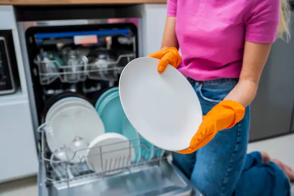年轻女人从洗碗机里拿出碗碟 — 图库照片