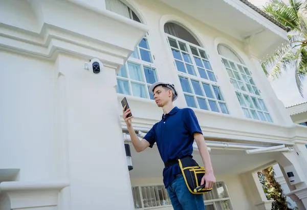 技術者は 住宅ビルの正面にCctvカメラをインストールします — ストック写真