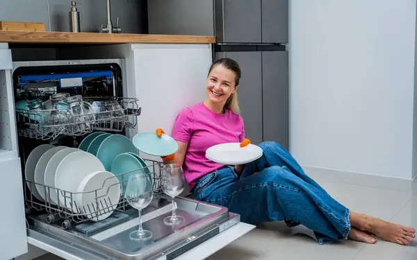Genç Bir Kadın Bulaşık Makinesinin Yanında Yerde Oturuyor — Stok fotoğraf