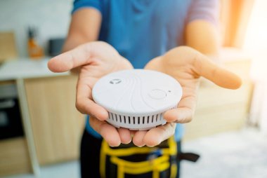 Modern bir apartmana yangın güvenlik detektörü yerleştiren teknisyen..