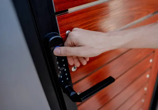 A technician installs a modern smart door lock on the wood door.