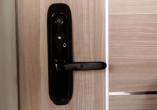 Modern smart door lock on the wooden door in a cozy apartment.