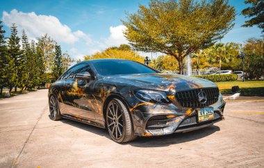 TELEFKET, THAILAND 24 ARALIK 2023: Güzel, parlak Mercedes AMG E53 palmiyelerle doğaya karşı.