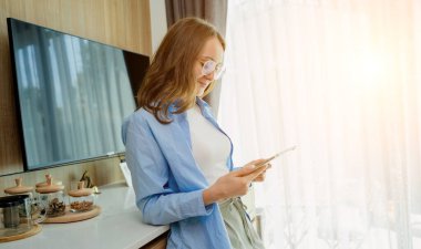 Tablet bilgisayardaki güvenlik kameralarına bakan genç bir kadın..