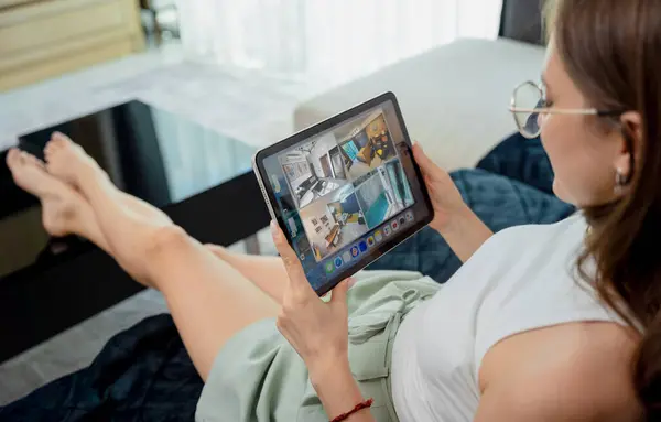 Young woman looking at home security cameras on tablet computer.