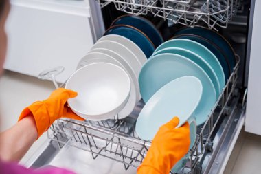 Genç kadın bulaşık makinesinden bulaşıkları çıkarıyor..