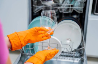 Genç kadın bulaşık makinesinden bulaşıkları çıkarıyor..