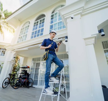 Bir teknisyen konut binasının ön cephesine kamera yerleştiriyor.