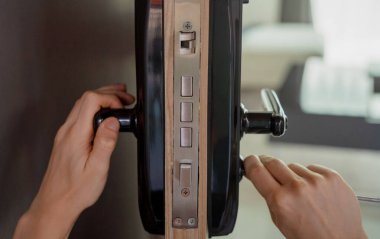 Bir teknisyen ahşap kapıya modern bir kapı kilidi takıyor..