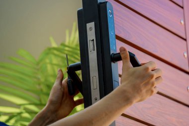 Bir teknisyen ahşap kapıya modern bir kapı kilidi takıyor..