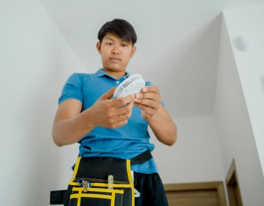 Modern bir apartmana yangın güvenlik detektörü yerleştiren teknisyen..