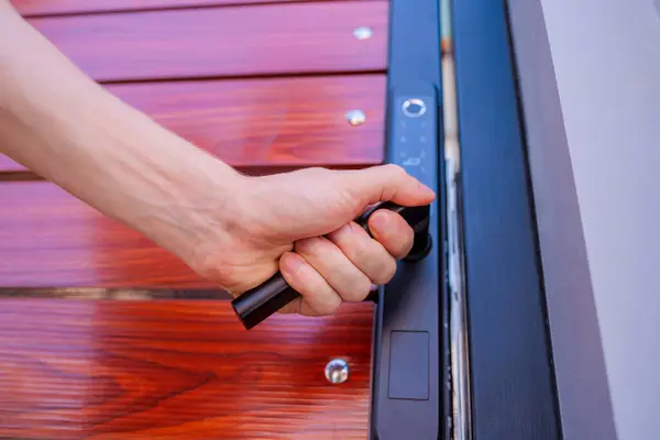 A technician installs a modern smart door lock on the wood door.