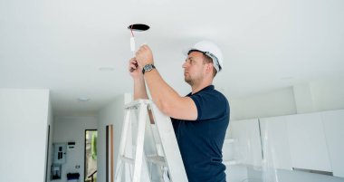 Teknisyen tavana bir LED spot ışığı yerleştiriyor.