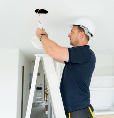Teknisyen tavana bir LED spot ışığı yerleştiriyor.