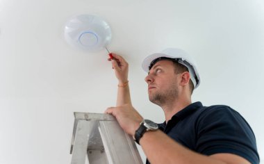 Teknisyen tavana bir LED spot ışığı yerleştiriyor.