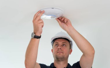 Teknisyen tavana bir LED spot ışığı yerleştiriyor.