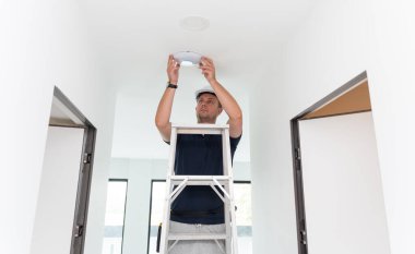 Teknisyen tavana bir LED spot ışığı yerleştiriyor.