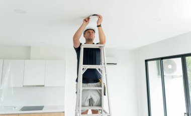 Teknisyen tavana bir LED spot ışığı yerleştiriyor.