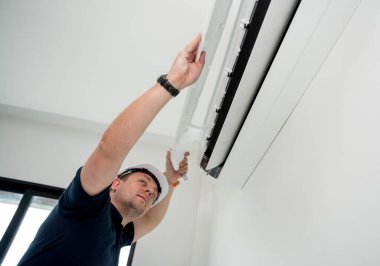 Teknisyen modern bir dairede klima sistemi temizliyor.