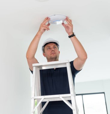 Teknisyen tavana bir LED spot ışığı yerleştiriyor.