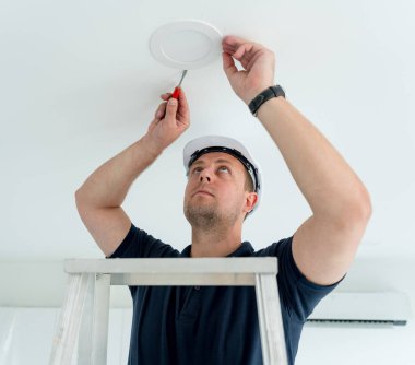 Teknisyen tavana bir LED spot ışığı yerleştiriyor.